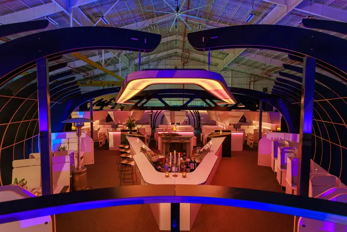 The cabin interior lit amber and violet, tables running the length of the fuselage