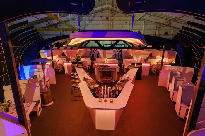The cabin from the aisle, seats and tables receding toward the far bulkhead