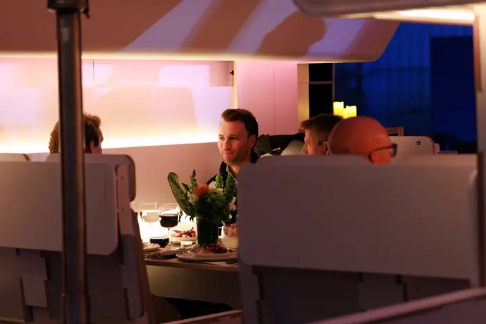 Guests seated at dinner inside the cabin mockup, lit warm