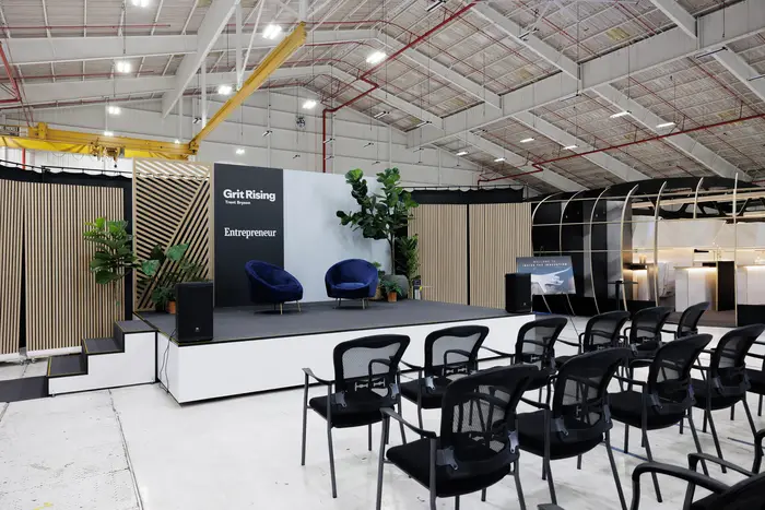 Rows of black chairs set facing the stage, with the lounge build behind