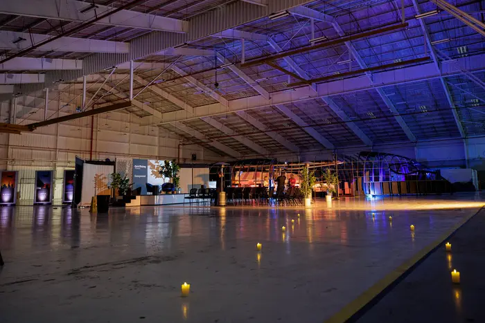 The hangar late in the evening, lighting dropped to blue and amber