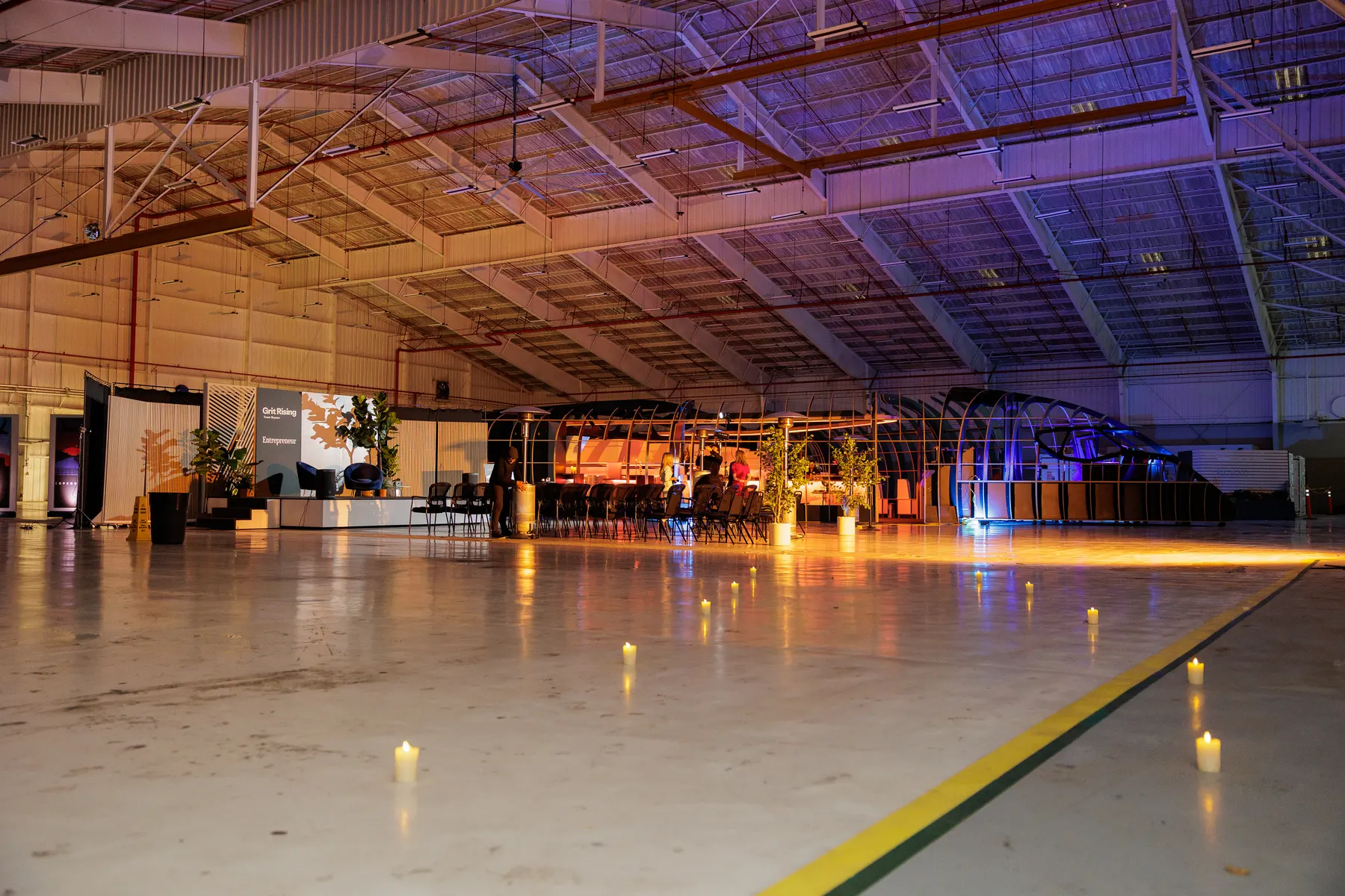 The JetZero hangar late in the evening, illuminated banner panels running down the length of the floor