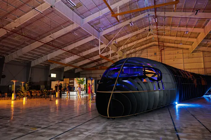 The full-scale cabin mockup in the hangar, lit blue along its length