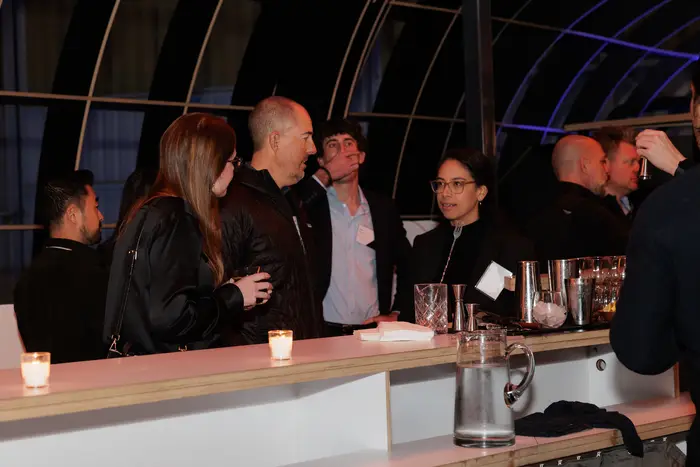 Guests at the bar as the room fills, name badges on lapels