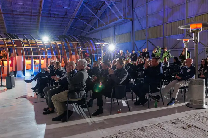 The audience from the side, the length of the hangar visible behind