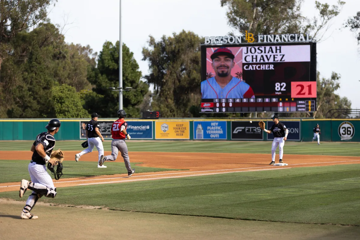 A runner rounds first as the videoboard shows the catcher's player card