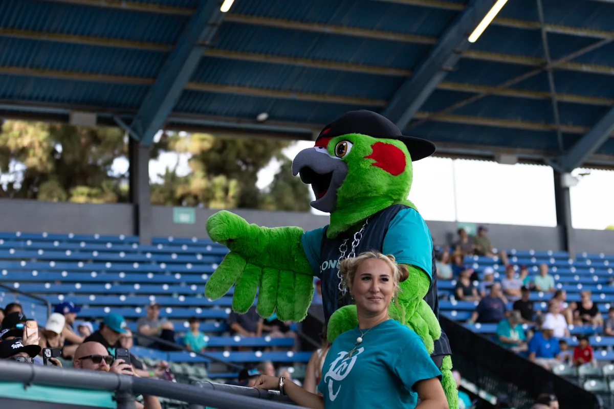 The mascot leaning into the crowd behind the netting