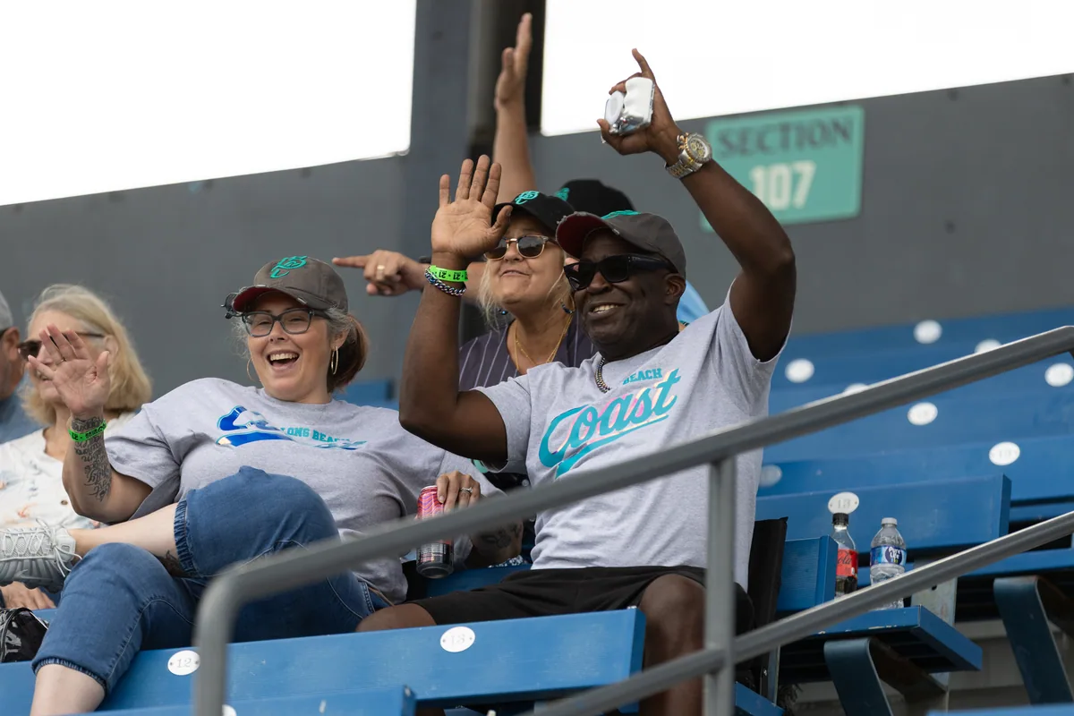 A man in the stands with both arms up after a play