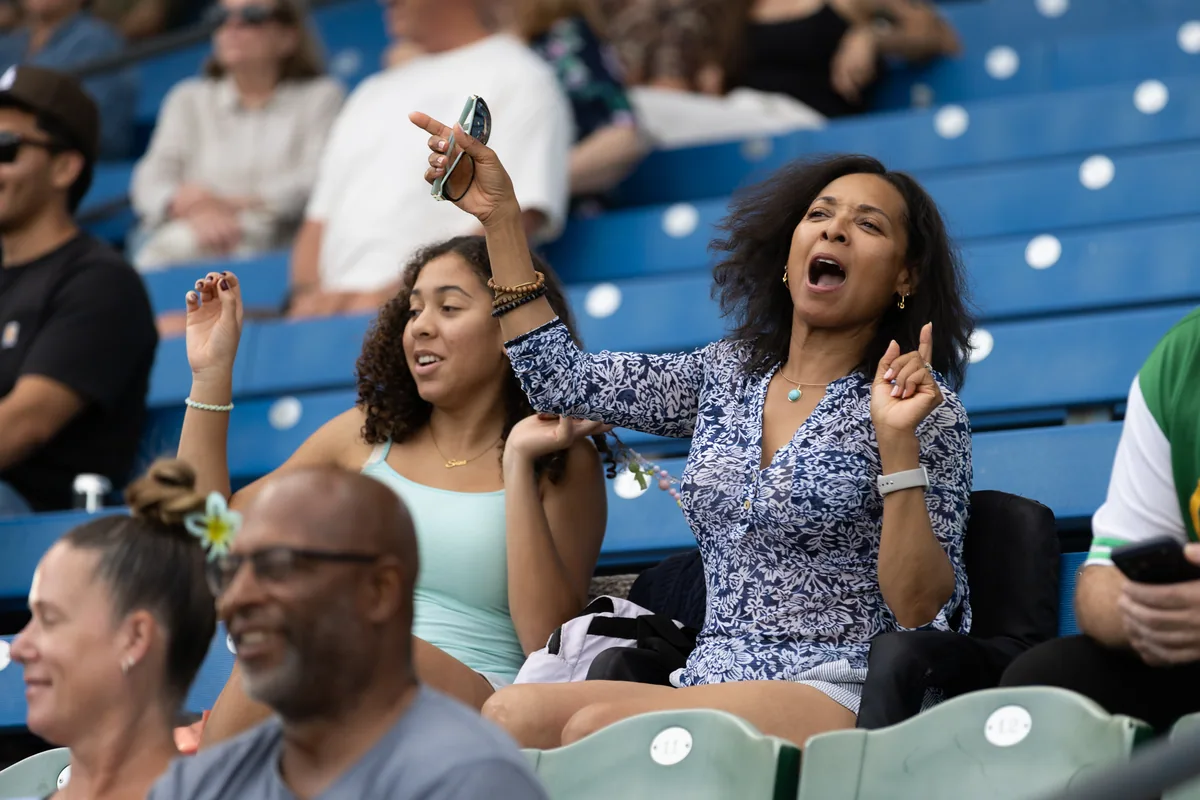 A woman on her feet cheering in the grandstand