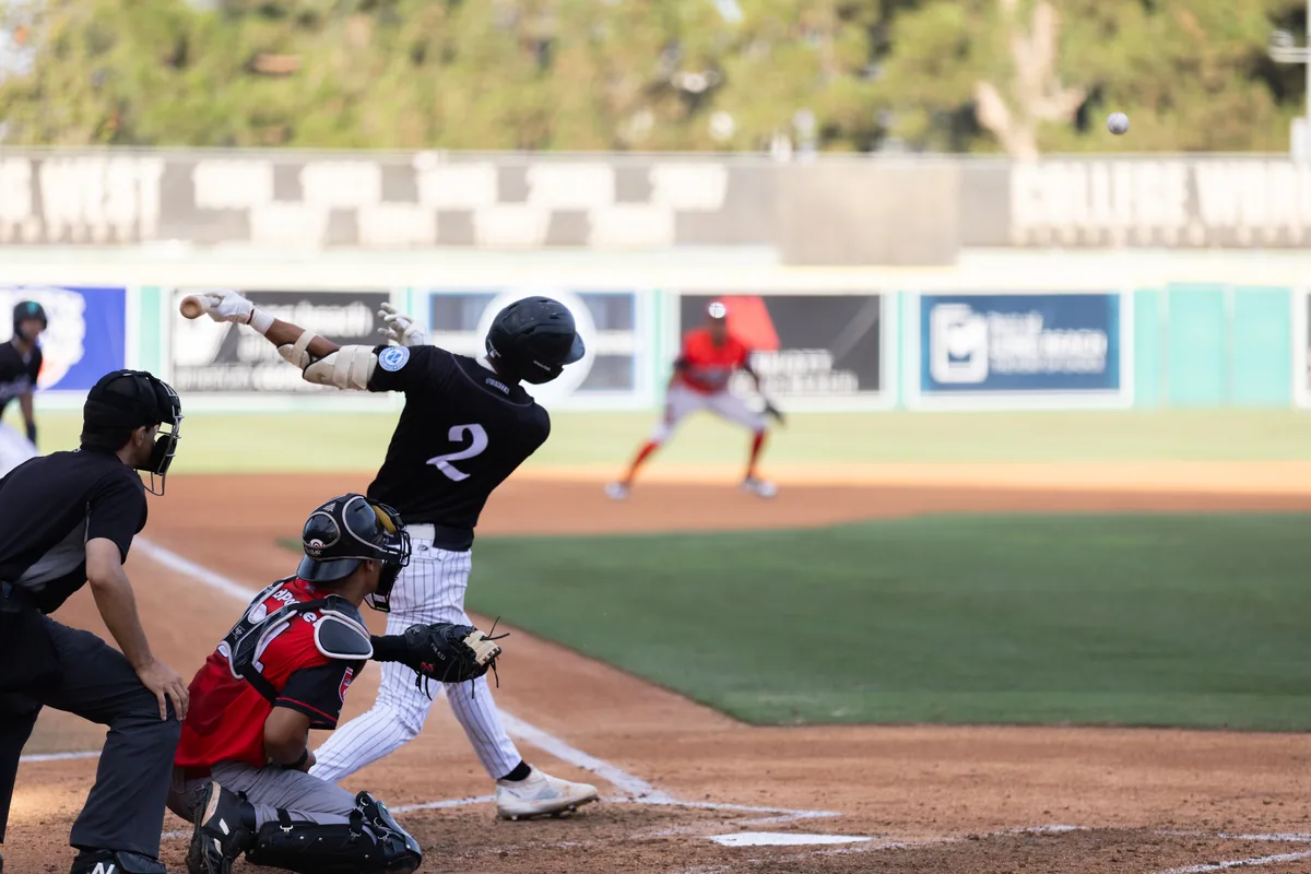 A batter makes contact, bat bending through the zone