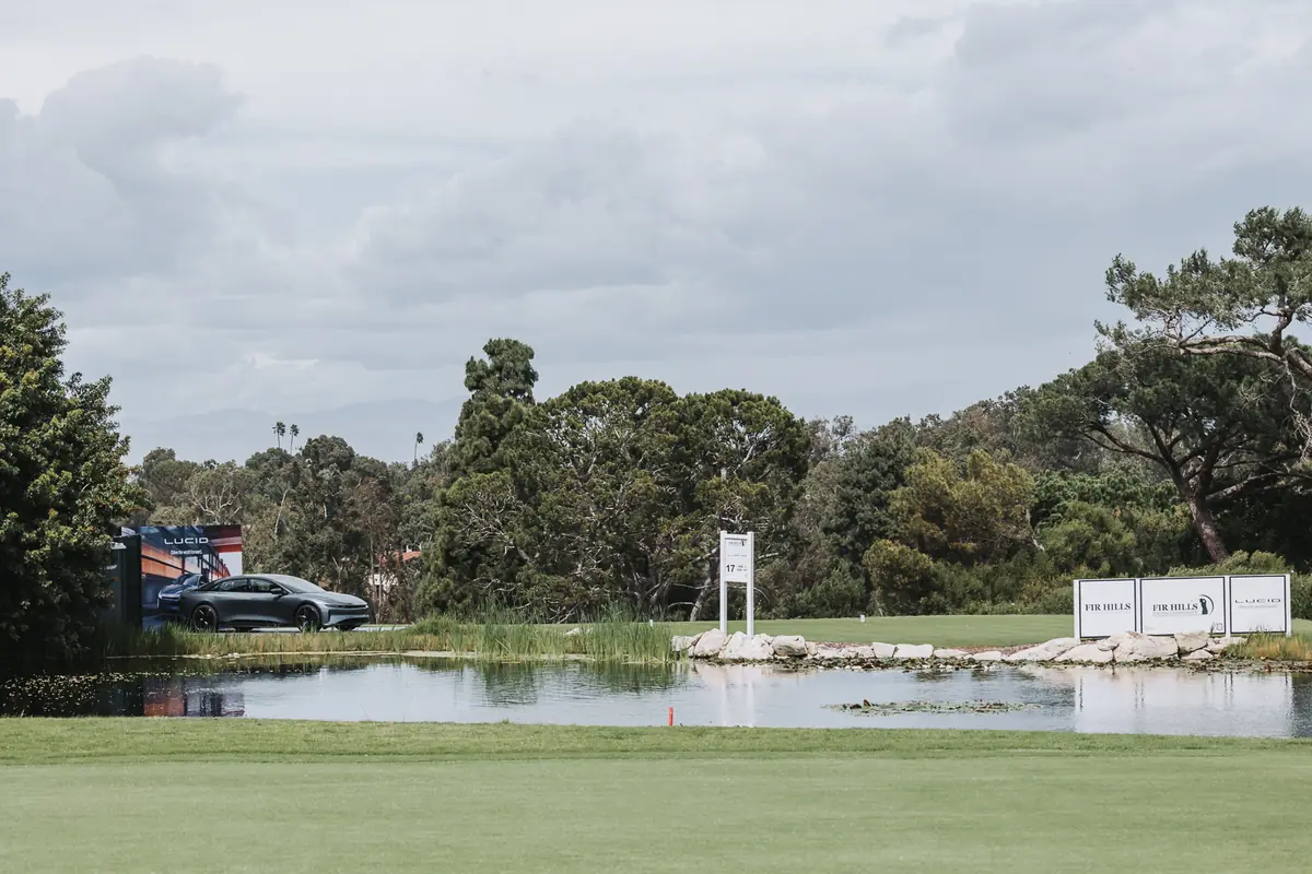 Still water on the course with tournament signage and the marshal's tent reflected behind it