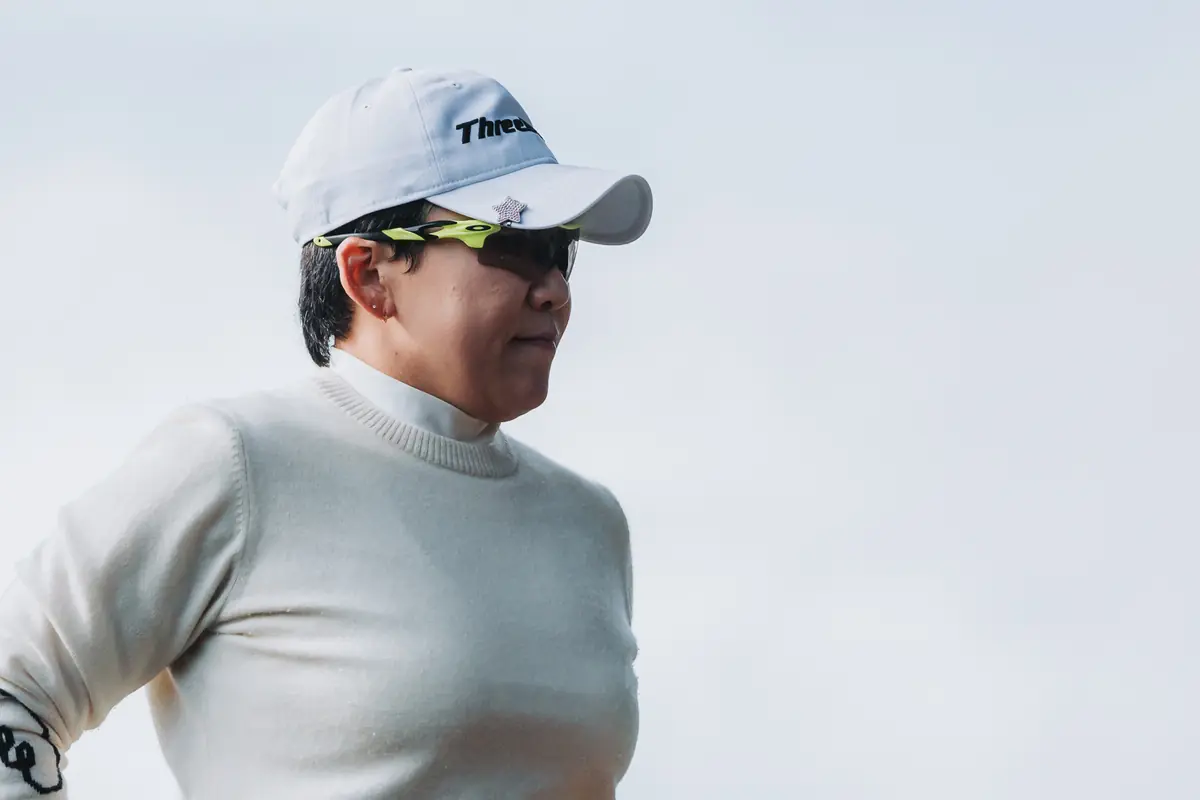 A player framed clean against open white sky on her way between holes