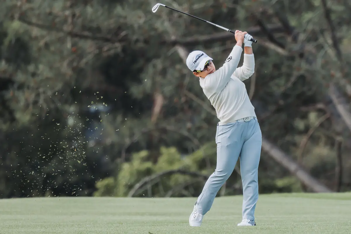 Full follow-through with turf still in the air, the player watching the ball out