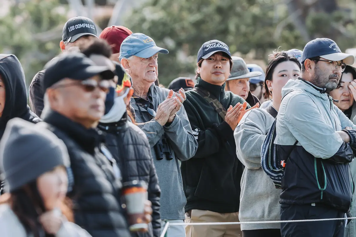 Spectators applauding at the ropes as a group walks off