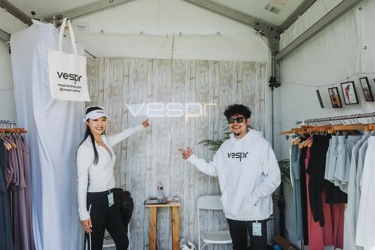 A branded apparel activation tent on the course, staff waving from inside