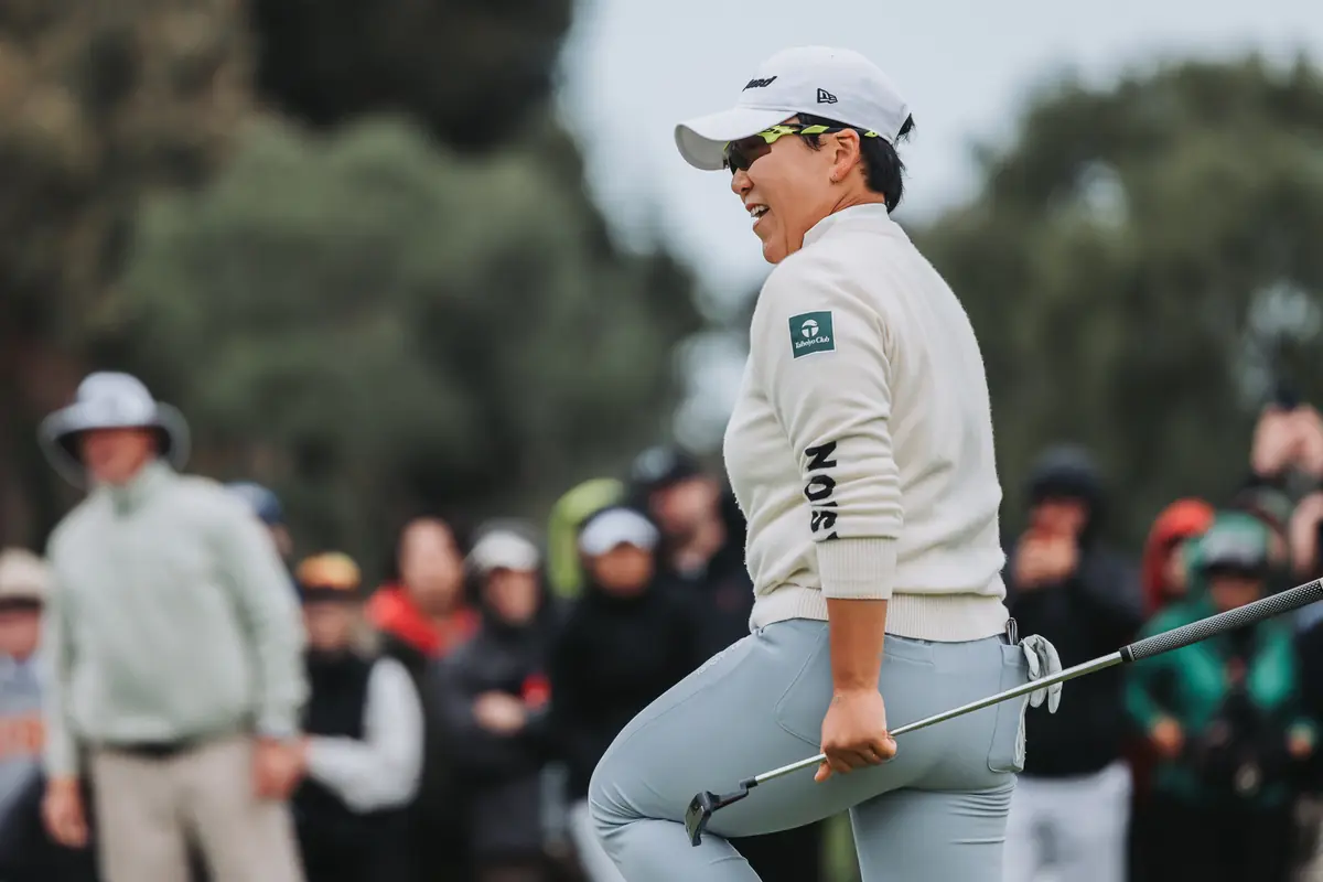 A player laughing on the 18th green with the putter still in her hand