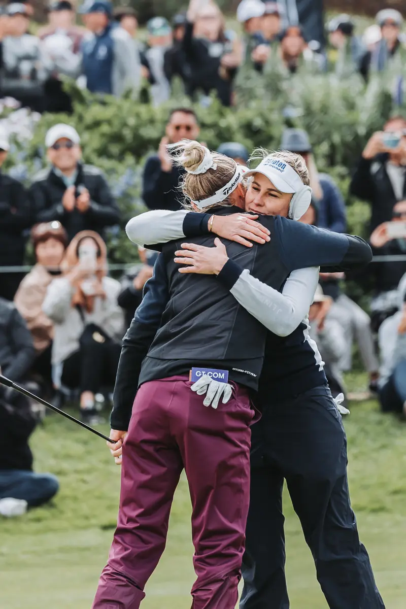 A long two-armed hug in front of a standing gallery after the finish