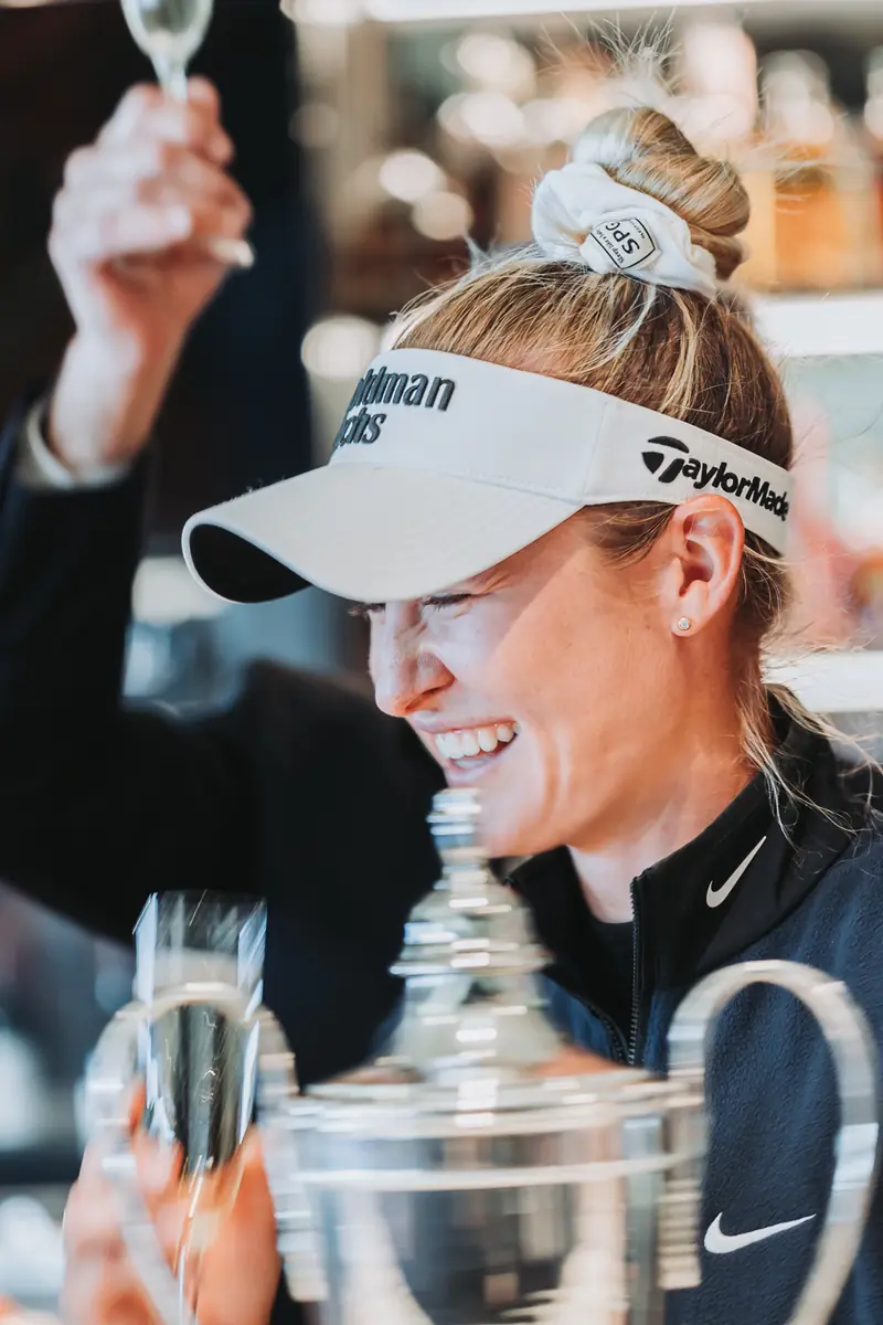 The champion laughing as she drinks from the trophy
