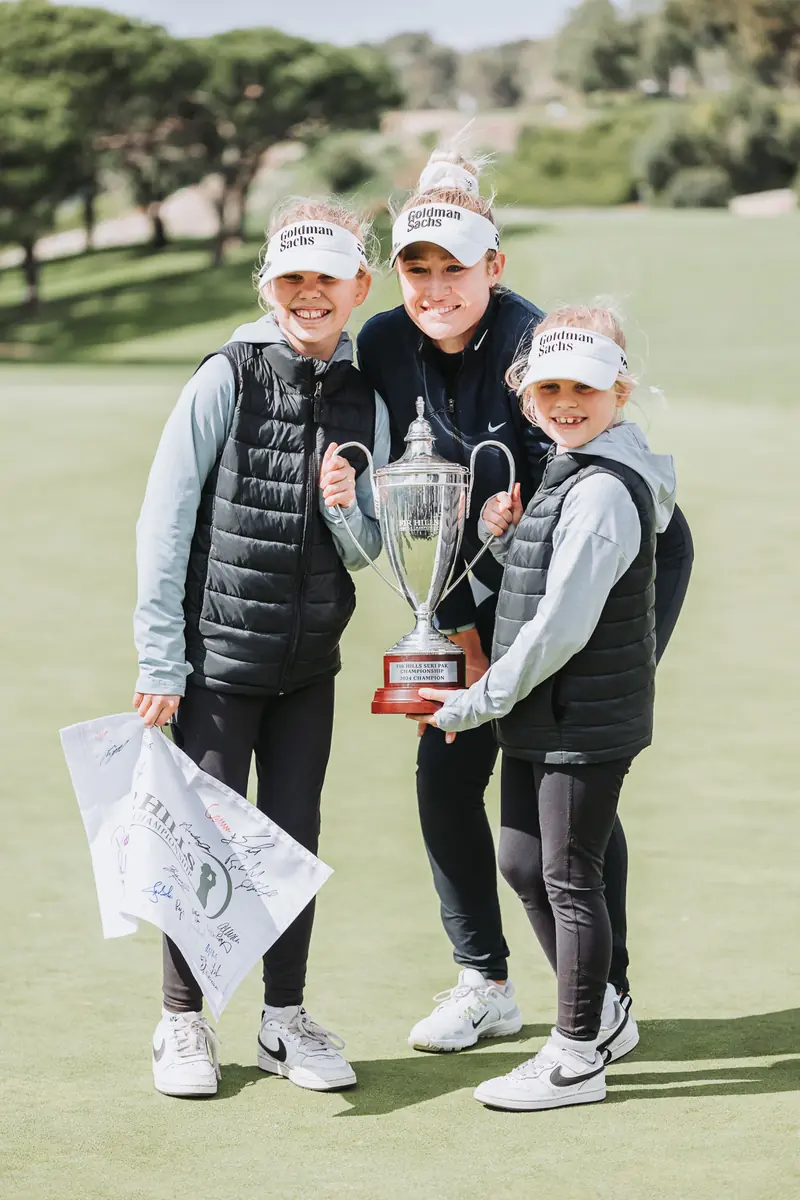 The champion with her team and family on the green, trophy between them