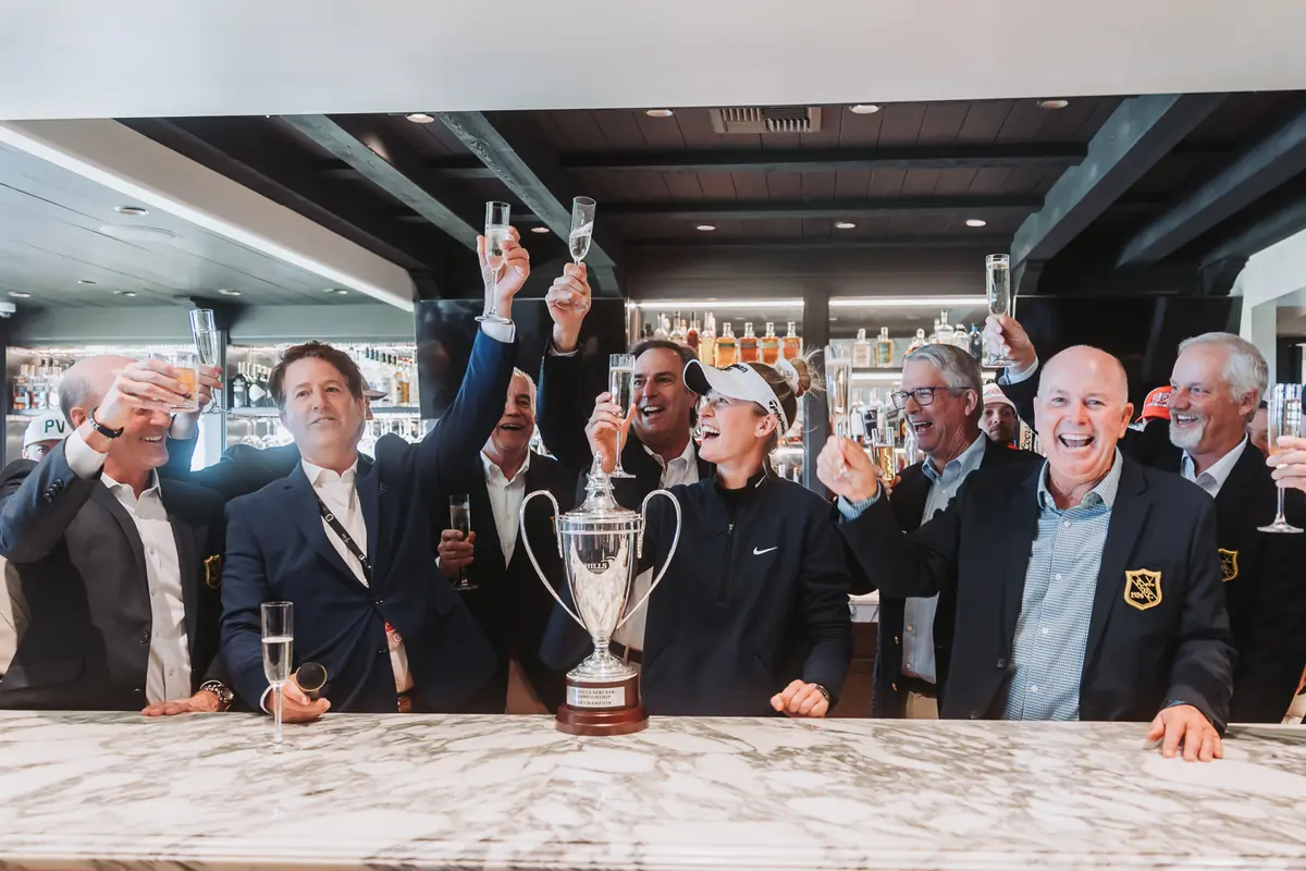 Glasses raised along the clubhouse bar at Palos Verdes Golf Club, the trophy on the marble between them