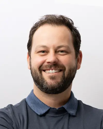 Team member in a slate polo, arms folded