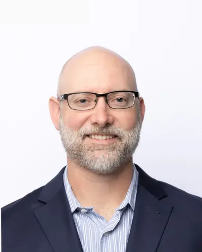 Team member in a navy blazer and glasses