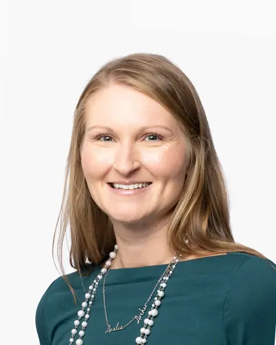 Team member in a teal top and long pearls