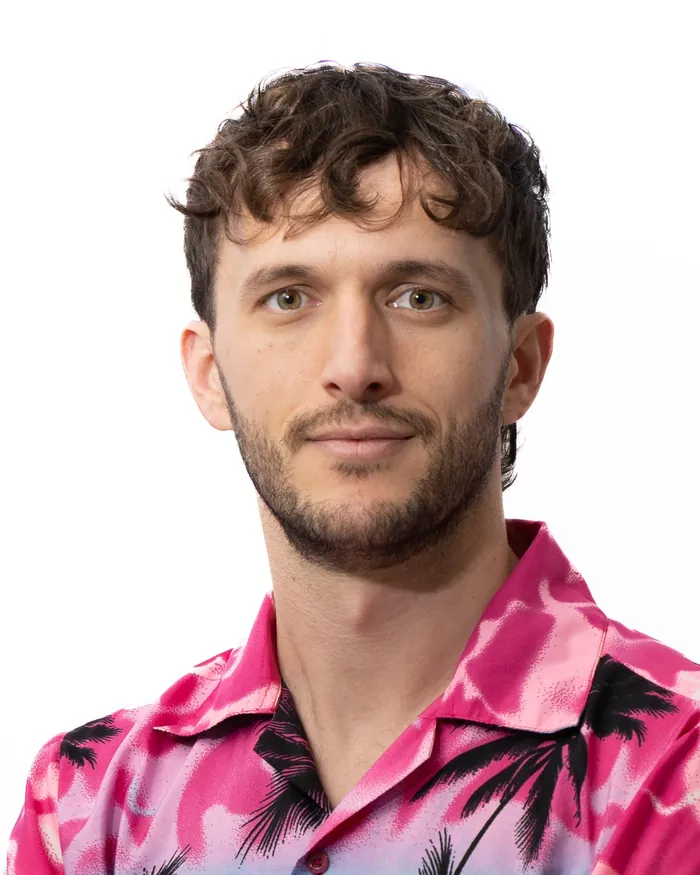 Team member in a patterned pink shirt on the same white backdrop