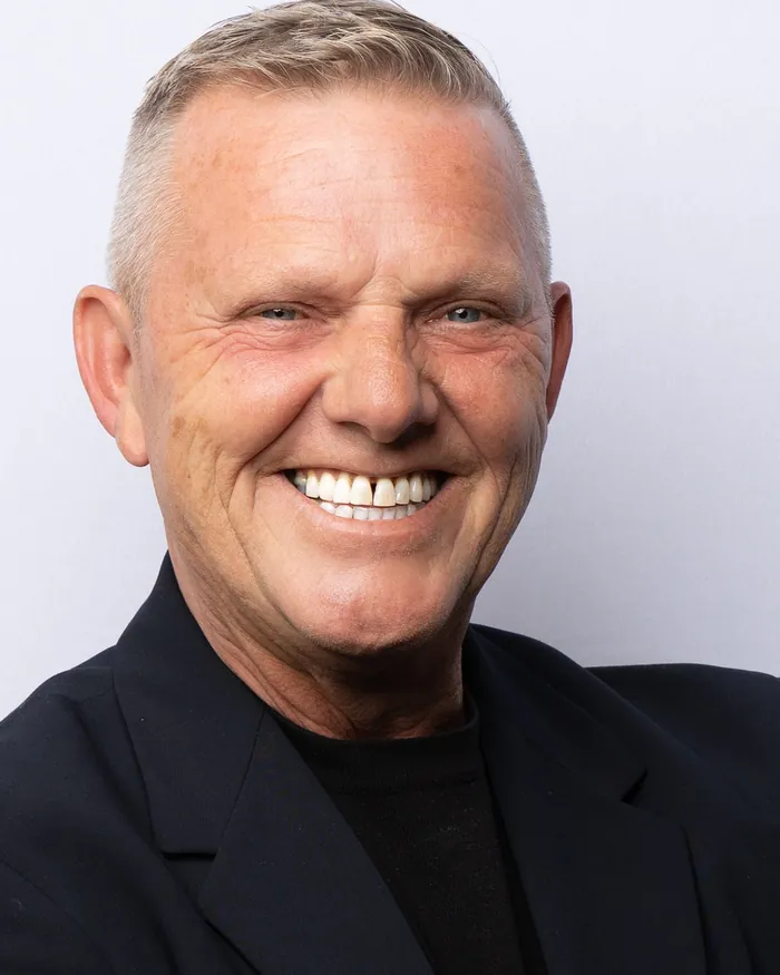 Executive in a dark blazer, arms folded, on the white studio backdrop