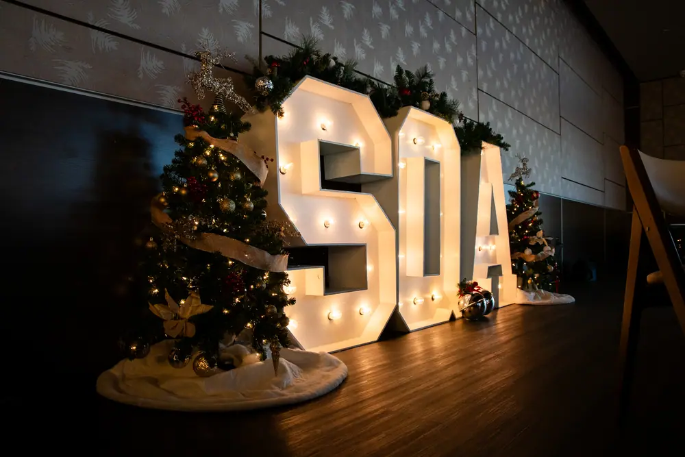 Illuminated SQA marquee letters draped in garland beside a decorated Christmas tree at Shade Hotel Redondo Beach