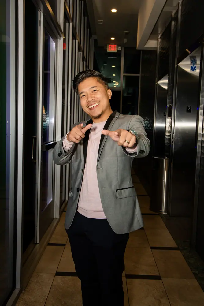 A guest stepping off the elevator at Shade Hotel Redondo Beach, grinning and pointing both hands at the camera
