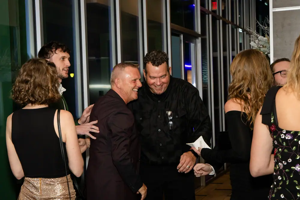 A handshake turning into laughter between two guests as the arrival corridor fills at Shade Hotel Redondo Beach