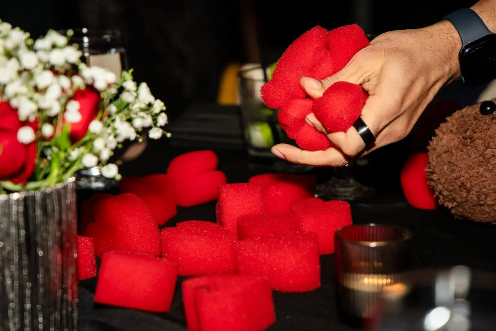A magician's hand holding a fistful of red sponge balls above a cocktail table