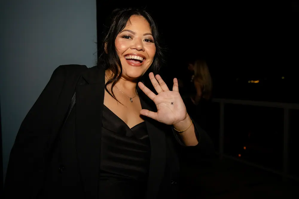 A guest laughing and holding up her palm to camera with a small star inked on it after a magic trick