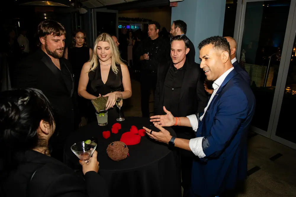 Four guests around a cocktail table watching a close-up magician work a trick