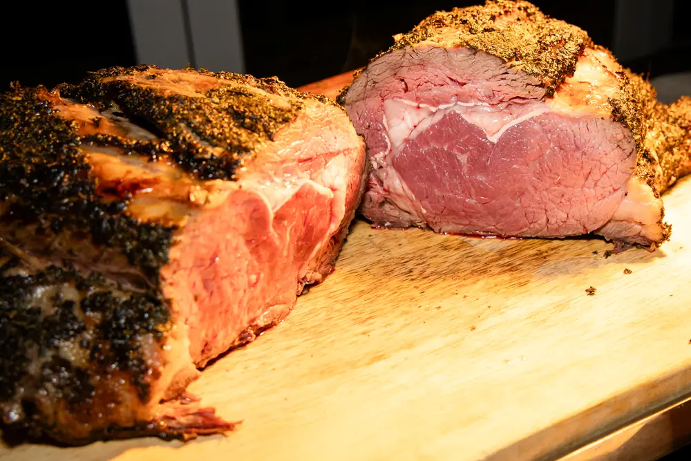 A carved prime rib on a wooden board under a heat lamp at the SQA Services anniversary dinner