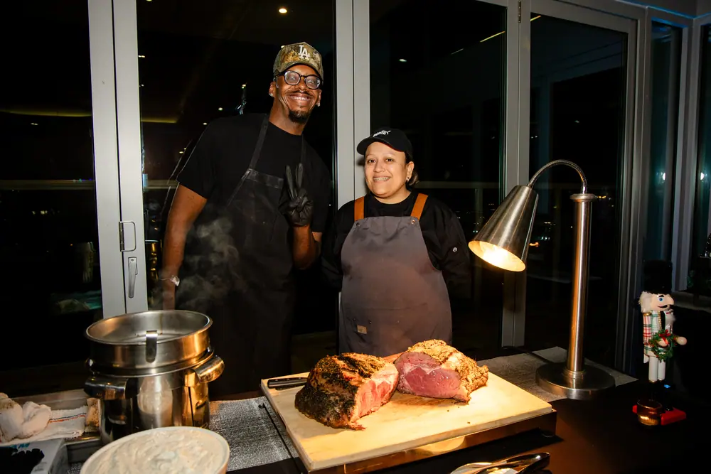 Two chefs grinning at the carving station, steam rising off the pans, at Shade Hotel Redondo Beach