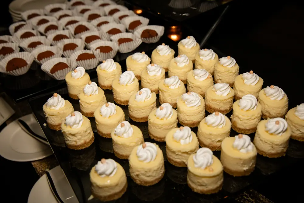 Trays of mini cheesecakes and chocolate cups on the dessert table at the anniversary party