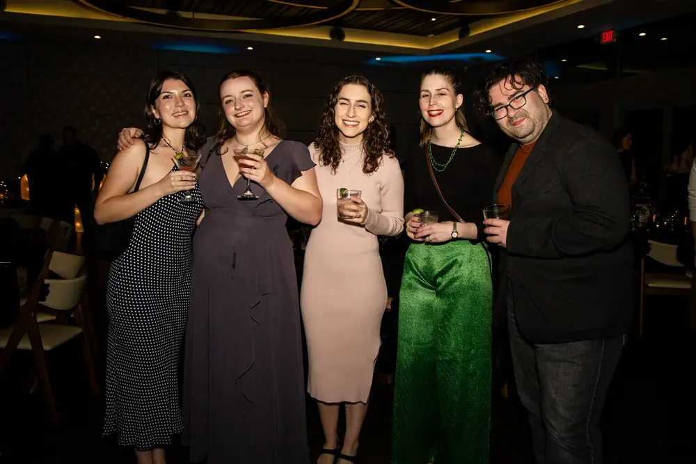 Five SQA Services colleagues lined up with cocktails, laughing at something off camera