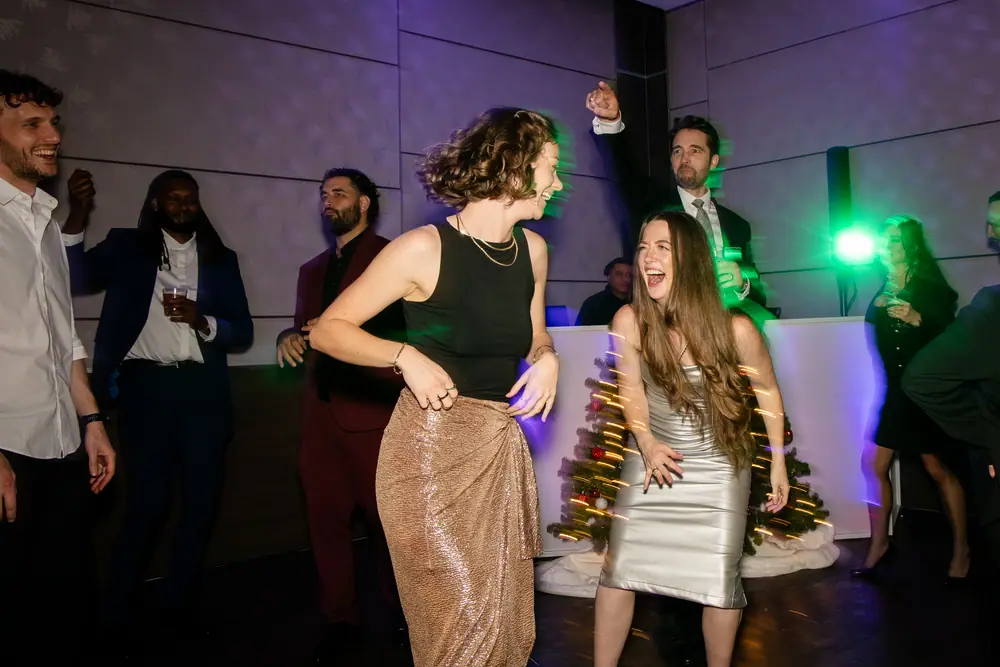 Two colleagues dancing, hair flying, one laughing with her head back