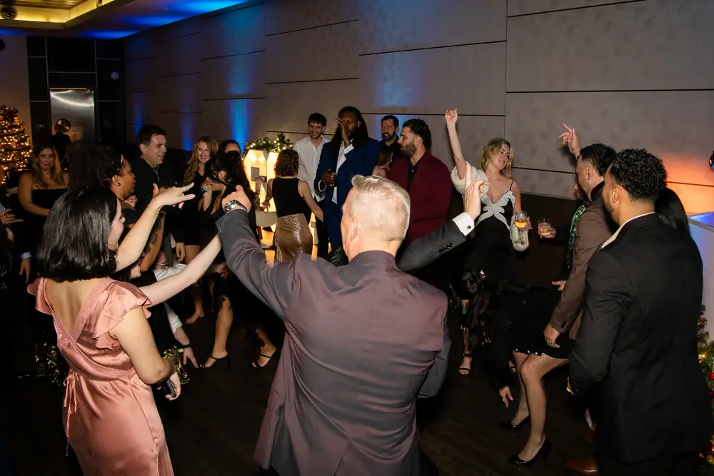 The whole floor dancing in a loose circle, arms up, near the end of the night