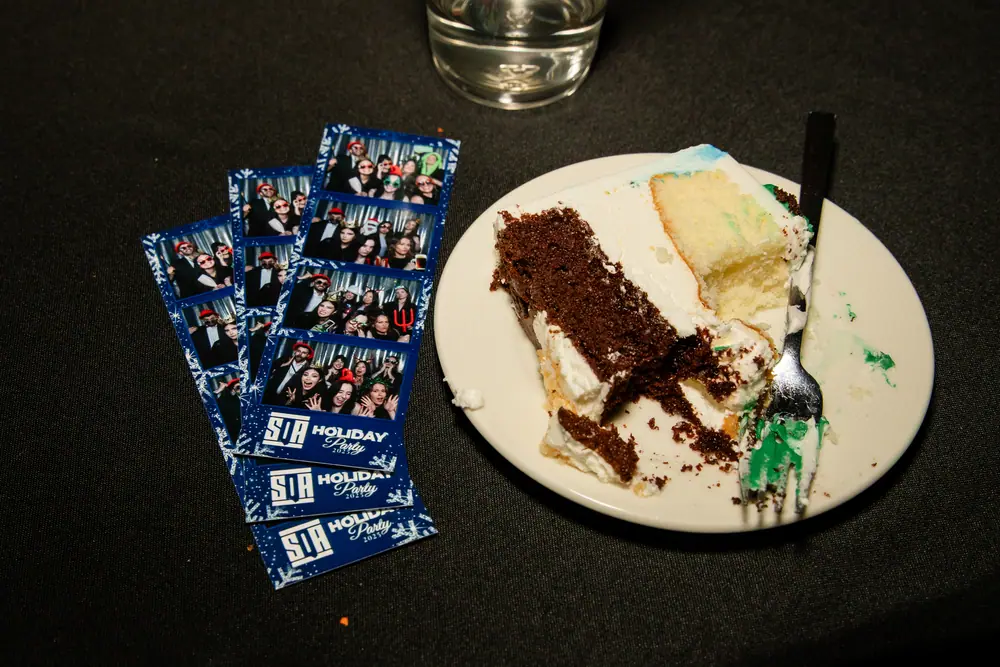 Photo booth strips beside a half-finished slice of the SQA 30th anniversary cake at the end of the night